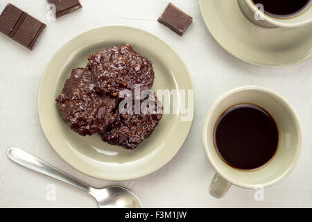 Reiche Schokolade Cookies in eine Untertasse neben Tassen schwarzen Kaffee und Schokolade Figuren Stockfoto
