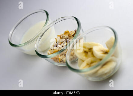 Kleine gesunde Frühstück mit Müsli, Milch und Banane Scheiben in klare Schalen auf weiß Stockfoto