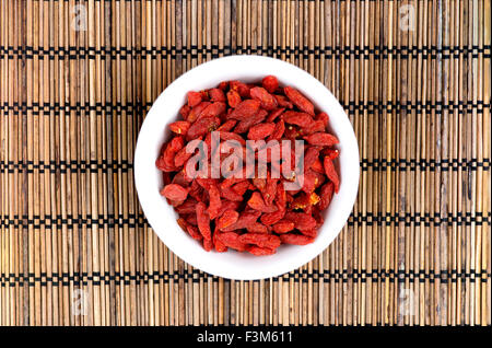 Goji-Beeren in Schüssel auf orientalische Matte weiß Stockfoto