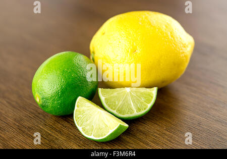 Schneiden von Limetten und Zitronen auf hölzernen Hintergrund Stockfoto