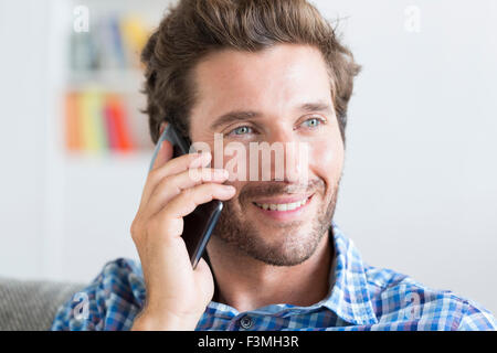 Lässige Mitte erwachsenen Mann am Telefon in modernen Wohnung Stockfoto