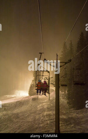 Zwei Mädchen reiten Ski heben beim Nachtskilauf, Silverton, Colorado. Stockfoto