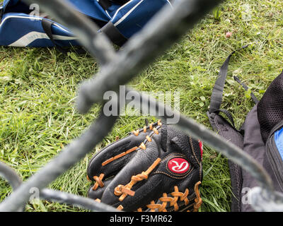 Baseball-Handschuh auf dem Boden gesehen durch ein Maschendrahtzaun. Stockfoto