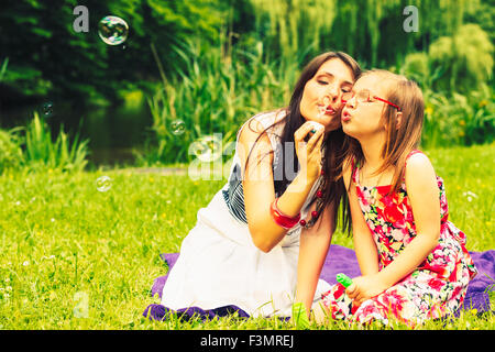 Mutter und Tochter Kind Seifenblasen im Freien. Elternteil und Kind Spaß im Park. Glückliche und unbeschwerte Kindheit. Gute fa Stockfoto