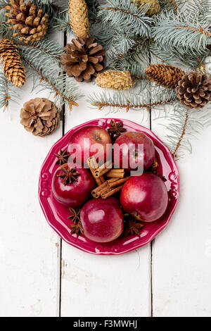 Weihnachten Äpfel und Gewürzen auf Holztisch mit Tannenzweigen und Zapfen. Selektiven Fokus. Stockfoto