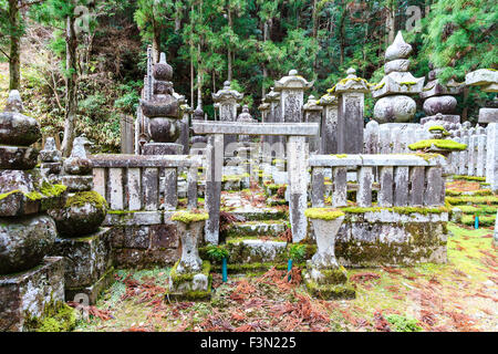 Japan, Koyasan, Okunoin Friedhof. Kleine Weg zu konkreten torii Tor mit erhöhten Bereich mit Stein Memorial Grabsteine im Zedernwald. Stockfoto