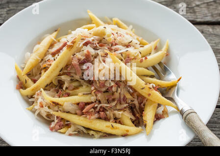 Finger geformte Kartoffelknödel mit Sauerkraut, Kümmel und Speck Stockfoto