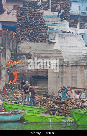 Arbeiter transportieren Holz für den Aufbau von Scheiterhaufen am Manikarnika Ghat am Fluss Ganges in Varanasi in den frühen Morgenstunden Stockfoto