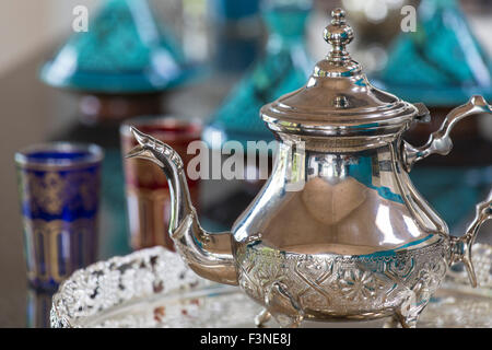 Marokkanische Teekanne mit Brille und Tagines im Hintergrund Stockfoto