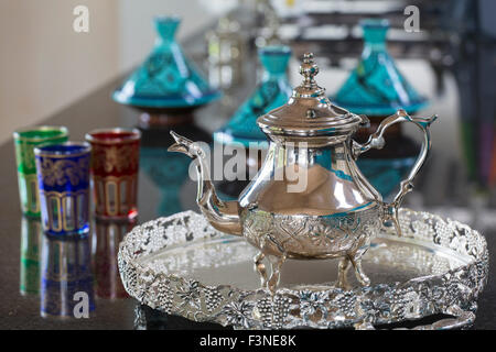 Marokkanische Teekanne mit Brille und Tagines im Hintergrund Stockfoto