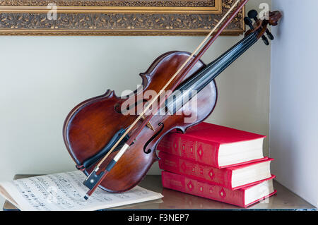 Violine Noten und Bücher stehen auf dem Tisch unter dem Gemälde Stockfoto