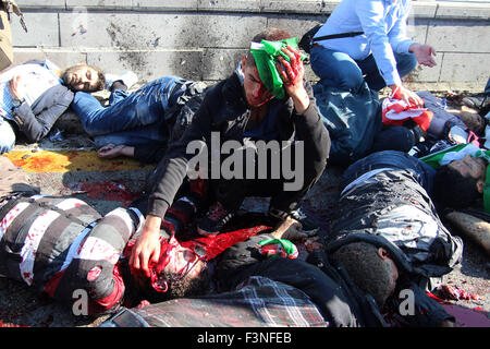 Ankara, Türkei. 10. Oktober 2015. Ein verletzter Mann sitzt unter den toten Opfern nach zwei Explosionen während einer Samstag Kundgebung für den Frieden passiert, von Gewerkschaften und Berufsverbänden organisiert. Er ist ein Überlebender in der Nachmahd der Zerstörung, nach zwei Bomben explodierten in der Nähe der türkischen Hauptstadt, Ankaras zum Hauptbahnhof. 86 Menschen getötet und verletzt 186. Die erste von zwei Explosionen fing eine Reihe von 14.000 Demonstranten Händchenhalten und Chanten, klopfte die Explosion Noten von ihnen auf den Boden an der Stelle, wo sie ihr Gepäck verlassen wurden, vor dem Eintritt in einen Kordon von Sicherheit für die Rallye Stockfoto