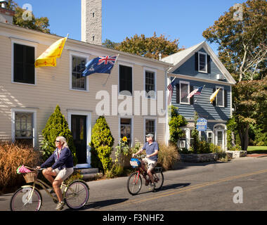 Paar Biken vor Gabriels Bed And Breakfast mit Pilgrim Monument im Hintergrund, Provincetown, Massachusetts, USA Stockfoto