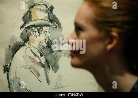 Ein Christie Mitarbeiter stellt mit Paul Cezanne des Künstlers "l 'Homme à la Pipe" bei Christies Auktionshaus in London, UK Freitag, 9. Oktober 2015.  .  Die Stücke werden voraussichtlich um zu erreichen US $ 100 Millionen Dollar und US $ 25 Millionen bzw., wenn es darum geht, Auktion.  Es ist auf Dispay im Vereinigten Königreich während der Kunstmesse Frieze Week bis Oktober 17 und will go on Verkauf in der "The Muse der Künstler: kuratiert Evening Sale" im Chrities New York am 9. November. Stockfoto
