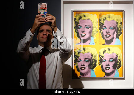 Francis Outred, Vorsitzender und Leiter der Nachkriegs und zeitgenössische Kunst emeritierte, posiert mit seinem Handy neben Künstler Warhols Kunstwerk "Vier Marilyns" bei Christies Auktionshaus in London, UK, 9. Oktober 2015.  Es ist auf Dispay im Vereinigten Königreich während der Kunstmesse Frieze Week bis Oktober 17 und will go on Verkauf im Nachkriegs und zeitgenössische Evening Sale bei Christie's New York am 10. November.  Kostenvoranschlag auf Anfrage erhältlich. Stockfoto