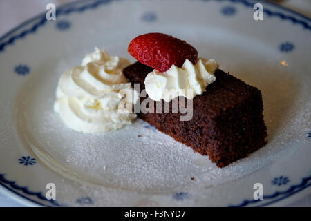 Schokoladenkuchen-Dessert mit Schlagsahne und einer Erdbeere Stockfoto