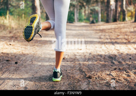 Läufer-Füße auf Straße Nahaufnahme am Schuh laufen. Frau Fitness bei Sonnenaufgang Stockfoto