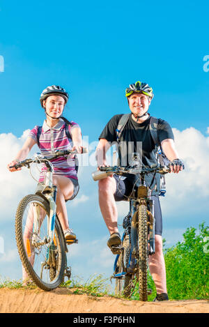 Vertikale Aufnahme eines lächelnden Paares auf dem Fahrrad Stockfoto