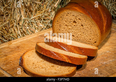 in Scheiben Roggenbrot auf einem Holzbrett in der Nähe von Heuhaufen Stockfoto