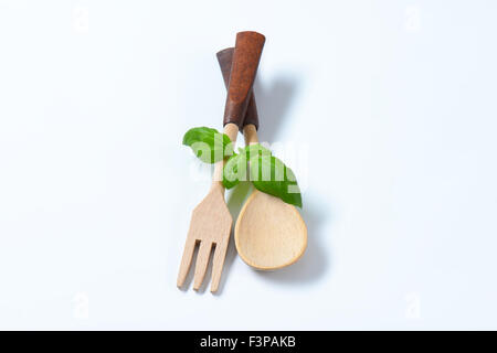 hölzerne Gabel und Löffel mit frischem Basilikum auf weißem Hintergrund Stockfoto