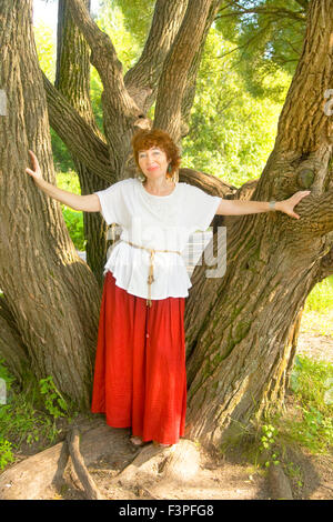 Europäerin mit Schuss braunen Haaren im roten Rock und weißer Bluse zu Fuß im Park, stehen in der Nähe von Weiden. Stockfoto