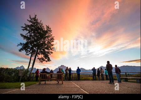 Touristen genießen Sie Blick auf den Sonnenuntergang von der Terrasse des berühmten & historischen Jackson Lake Lodge; Grand Teton Nationalpark; Teton Range Stockfoto