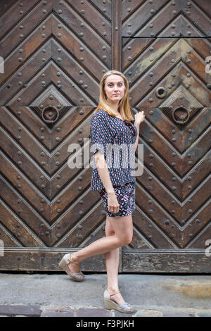 Junge Frau steht vor einer alten Tür. Stockfoto