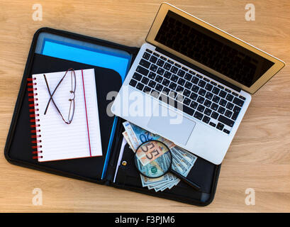 Ordner für Dokumente mit Dollars und Euro Rechnungen, Notizblock, Gläser und Laptop auf eine hölzerne Struktur Oberfläche Draufsicht. Stockfoto