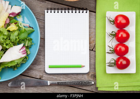 Frische gesunde Salat, Tomaten und Notizblock für textfreiraum auf Holztisch Stockfoto