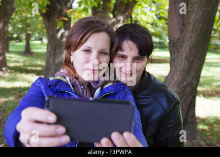 junge Frau mit ihrer Mutter, die Bilder von sich selbst ein Handy auf Herbsttag außerhalb Stockfoto