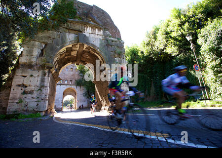 Rom, Italien. 11. Oktober 2015. Radfahrer fahren, vorbei an einem römischen Bogen entlang der antiken Via Appia während der historischen Radsport-Event "Granfondo Campagnolo Rom" in Rom, Italien, am 11. Oktober 2015. Die Veranstaltung lockte 5200 Radfahrer aus 40 Ländern und Regionen. Radfahrer gestartet vom Kolosseum entfernt, Symbol der ewigen Stadt, Radfahren zu historischen Sehenswürdigkeiten im antiken Rom, des Flusses Tiber und Venedig Platz, und reiste zu den römischen Hügeln. Schließlich fuhren sie vorbei an den Pflastersteinen der antiken Via Appia, die Ziellinie zu überqueren. Bildnachweis: Jin Yu/Xinhua/Alamy Live-Nachrichten Stockfoto