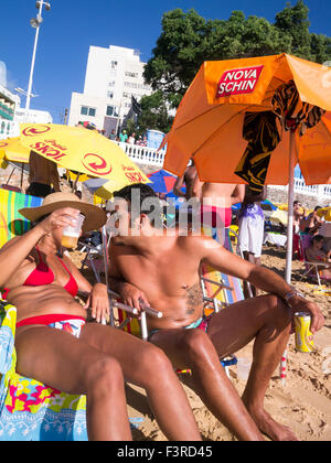 SALVADOR, Brasilien - 13. Oktober 2013: Lokale Brasilianer entspannen Sie an einem hellen Sommernachmittag am Porto da Barra Strand. Stockfoto