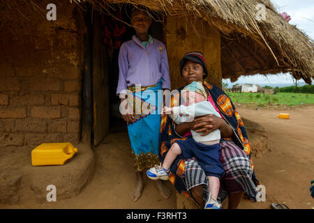 Frau mit Albino Junge sitzt vor ihrem strohgedeckten Hütte, Mosambik, Afrika Stockfoto