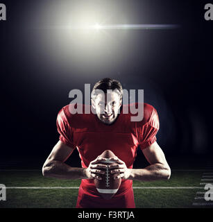 Zusammengesetztes Bild von aggressiven american Footballspieler in roten Trikots mit ball Stockfoto