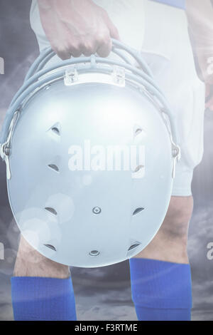Zusammengesetztes Bild des Mittelteils des american Footballspieler übergibt seinen Helm Stockfoto
