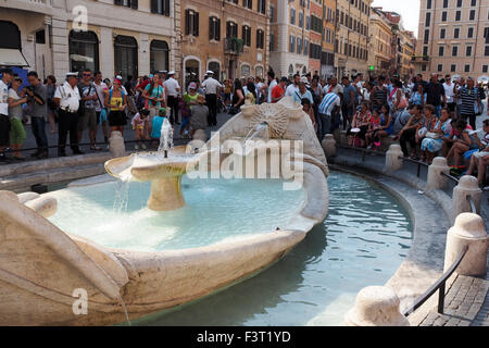 Touristen, die Fräsen rund um den Brunnen des Ugly Boots (Fontana della Barcaccia) in der Piazza di Spagna, Rom. Stockfoto