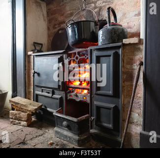 Ein Kaminfeuer in einer Gusseisen-Reihe in einer restaurierten Bergarbeiter Hütte am Blakemoregate, in der Nähe von Snailbeach, Shropshire. Stockfoto