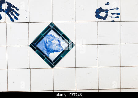 blaue und weiße Fliesen mit Bild eines Schweins und Handabdrücke Stockfoto