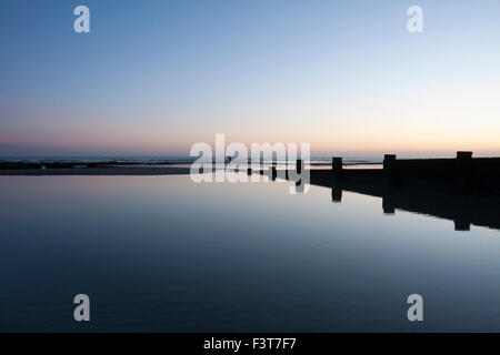 Reflexionen in der Dämmerung und einsame Abbildung auf einem ruhigen Strand, Bexhill-on-Sea, East Sussex, England, Großbritannien Stockfoto