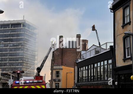 Bristol, UK. 12. Oktober 2015. Ein Großbrand begann ca. 13:00 h im University of Bristol Studentenwohnheim, 33 Colston Straße, Bristol, England, 12. Oktober 2015, von Avon Feuer & Rettungsdienste mit zwei Plattenspieler Leiter Feuerwehrfahrzeuge und mehr als vier weitere Module in Angriff genommen. Die Lage ist zwischen der Colston Hall und Griffin Pub in der Nähe der Kreuzung der Colston und Trenchard Street und diese Straßen für Fahrzeuge und Fußgänger geschlossen worden. Das Feuer hat die gesamte Länge des Daches und obersten Etage vollständig zerstört. Bildnachweis: Charles Stirling/Alamy Live-Nachrichten Stockfoto