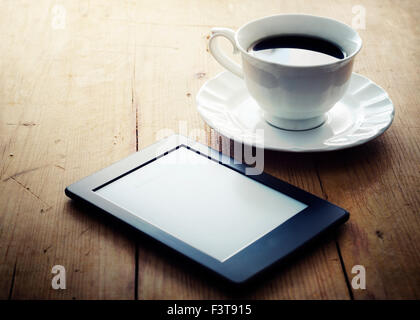 E-Book-Reader und Kaffeetasse auf Holztisch Stockfoto