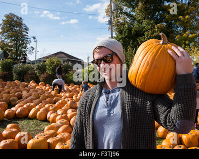 Shopper mit Kürbis auf Schultern vom Bauernmarkt während kanadische Thanksgiving-Wochenende. Stockfoto