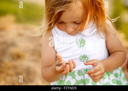 Kleines Mädchen hält eine grüne Eidechse auf seinem Arm. Ich lerne Konzept der Welt. Kinder und Tiere. Stockfoto