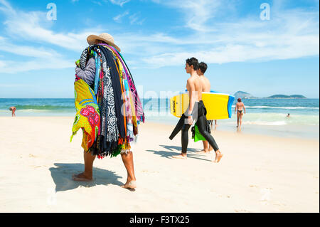 RIO DE JANEIRO, Brasilien - 13. Januar 2013: Junge brasilianische body Boarder Pass einen Kreditor Kanga Sarongs am Strand von Ipanema zu verkaufen. Stockfoto