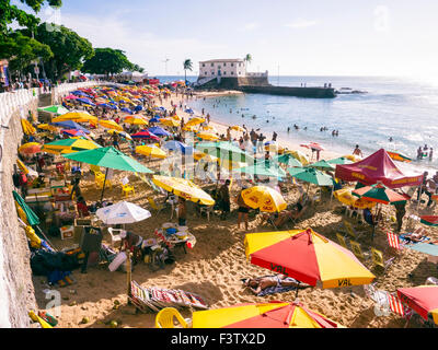 SALVADOR, Brasilien - 13. Oktober 2013: Beachgoers versammeln sich unter bunten Sonnenschirmen am hellen Nachmittag am Porto da Barra. Stockfoto