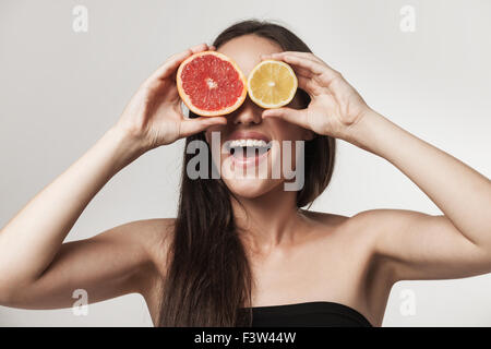 lustige Portrait schöne junge Brünette Frau mit frisch geschnittenen Grapefruit und Zitrone. Ernährung Gesundheit und Gewicht Stockfoto