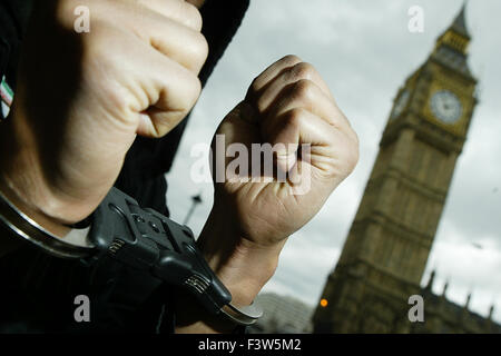 Ein Mann posiert vor den Houses of Parliament während des Tragens Polizeihandschellen. Stockfoto