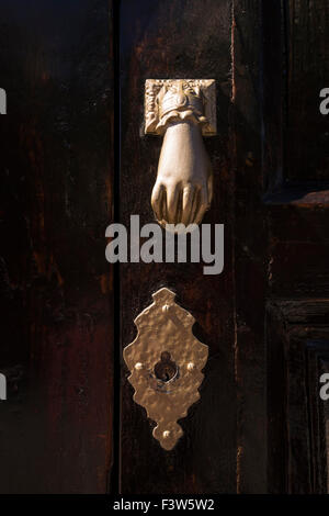 Alte verzierte Hand geformten Türklopfer und Schlüsselloch auf eine dunkle Holztür. Stockfoto