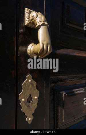 Alte verzierte Hand geformten Türklopfer und Schlüsselloch auf eine dunkle Holztür. Stockfoto