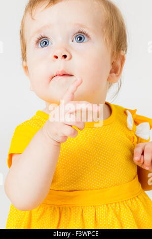 Kleines Mädchen im gelben Kleid auf einem hellen Hintergrund. Stockfoto